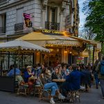 a group of people sitting at tables outside of a restaurant