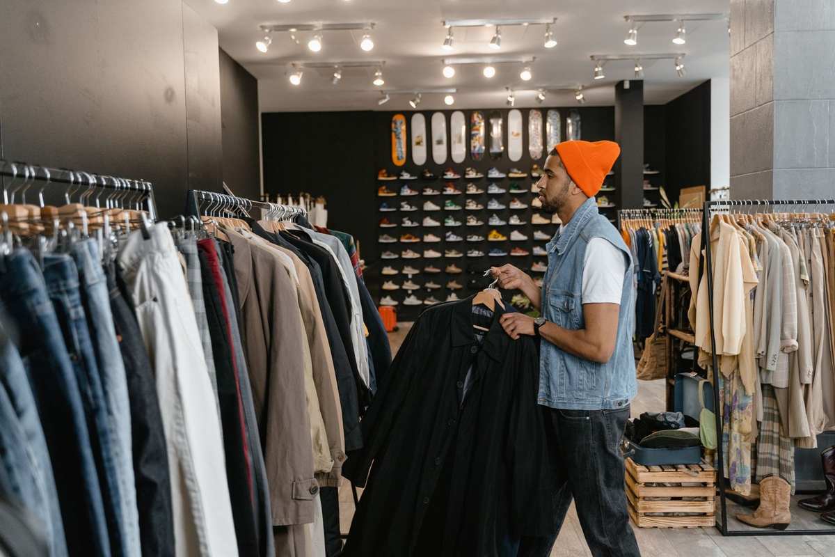 Homme en magasin, inspecte des vêtements sur des étagères Homme en magasin, inspecte des vêtements sur des étagères