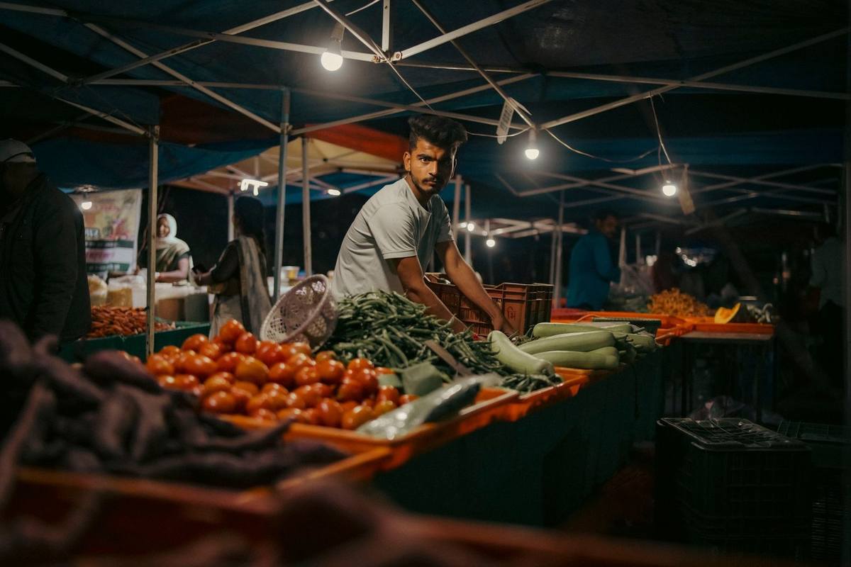 Marché de légumes avec tomates et courgettes sous une tente éclairée