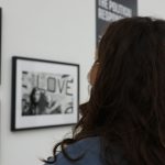 a woman standing in front of a wall with pictures on it